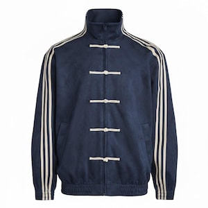 May include: A navy blue track jacket with cream stripes on the sleeves and collar. It has a high collar, a zip, and toggle closures down the front. The jacket has a sporty design with a classic feel. The jacket is suitable for casual wear.