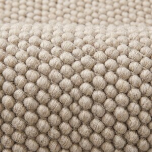 Close view of oversized loop texture rug showing thick natural yarn structure