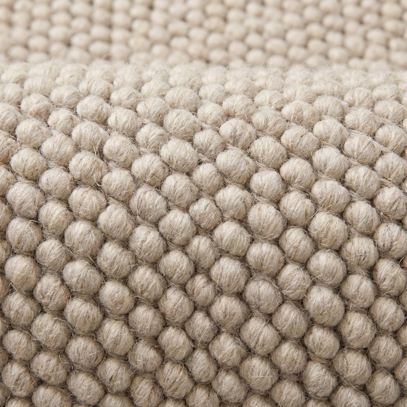 Close view of oversized loop texture rug showing thick natural yarn structure