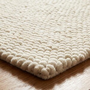 Edge detail of thick hand-textured wool rug with rounded loop construction