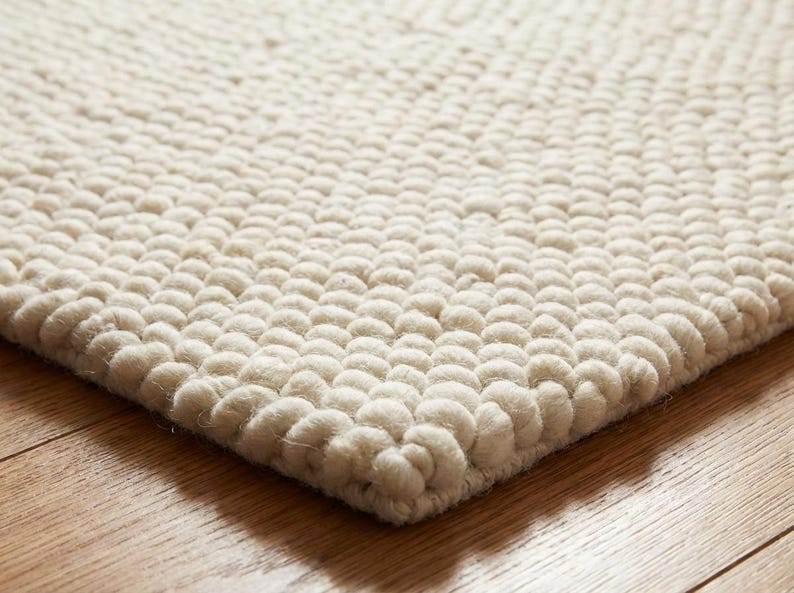 Edge detail of thick hand-textured wool rug with rounded loop construction