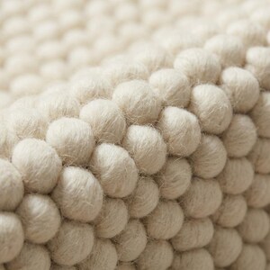 Close-up of oversized wool loops showing deep pebble texture in neutral ivory rug