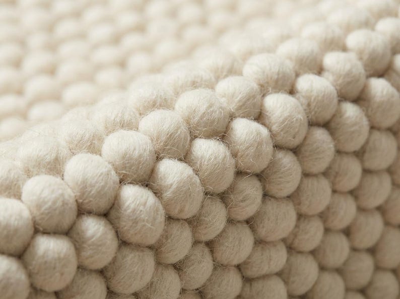 Close-up of oversized wool loops showing deep pebble texture in neutral ivory rug