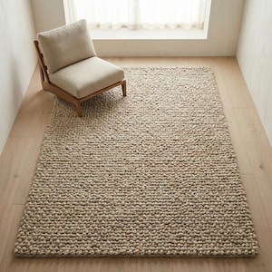 Puede incluir: Una alfombra beige texturizada con una pila gruesa y en bucle. Una silla de madera con un cojín beige está sobre la alfombra. La alfombra rectangular cubre una gran parte del suelo de madera clara.