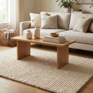 Scandinavian living room featuring chunky neutral wool rug and soft lounge chair