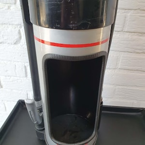 Op de afbeelding: Een zwarte en zilveren biertap met een rode streep en het woord "Grolsch" in het rood. De tap heeft een grote opening en is gemonteerd op een zwarte lade.