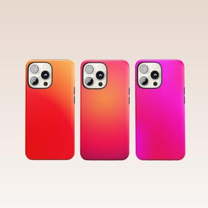 May include: Three brightly coloured phone cases in red, orange, and pink. Each case has a camera cutout and side buttons. The cases are arranged side by side against a neutral background.