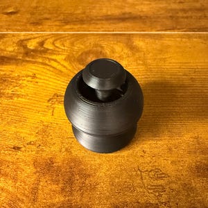 以下が含まれることがあります： 丸みを帯びたベースと円筒形のトップを備えた黒いボトルストッパー。ストッパーは頑丈な素材で作られており、表面はテクスチャ加工されています。 デザインはシンプルでモダンで、さまざまな種類のボトルに適しています。