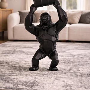 May include: A black gorilla statue with a barrel held overhead. The gorilla has an open mouth and a geometric design. The statue is on a patterned rug in a living room setting.