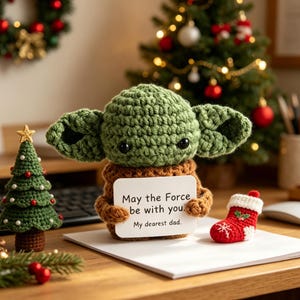 May include: A crocheted green character doll with large ears holds a sign that reads "May the Force be with you. My dearest dad." A small crocheted Christmas tree and red stocking are also present.