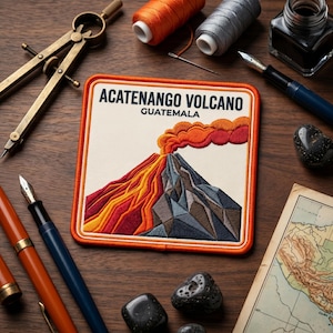 May include: A square embroidered patch featuring the text ACATENANGO VOLCANO GUATEMALA above a depiction of a volcano with orange and red lava flows and a plume of smoke, surrounded by drafting tools, fountain pens, thread spools, and a map.