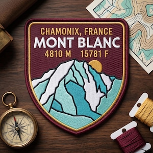 May include: A burgundy and gold embroidered patch featuring the text "CHAMONIX, FRANCE MONT BLANC" and mountain graphics. The patch also includes the elevation in meters and feet: 4810 M 15781 F. A compass and map are in the background.