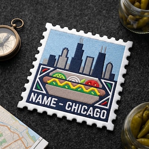 May include: Embroidered patch in the shape of a postage stamp featuring a Chicago-style hot dog and the city skyline. The patch has a light blue background and the text "NAME - CHICAGO".