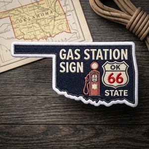 May include: Embroidered patch in the shape of Oklahoma, navy blue with white border. Text reads "GAS STATION SIGN" and "OK 66 STATE" with a vintage gas pump graphic. A map and rope are in the background.
