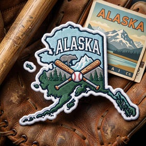 May include: An Alaska-themed patch in the shape of the state, featuring a bear, crossed baseball bats, and a baseball. The patch is on a baseball glove with a vintage Alaska postcard.