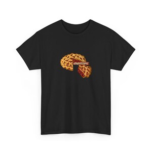 Puede incluir: Camiseta negra con un gráfico de una tarta con una porción cortada. La tarta tiene una corteza dorada y un relleno rojo. El texto "Sweetest Little Pie" está en la tarta. Una porción de tarta está al lado de la tarta.