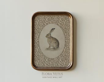 May include: A framed print with a vintage aesthetic, depicting a hare illustration. The hare is in an oval frame, set against a floral pattern. The frame is a warm gold colour. The text "FLORA VETUS HERITAGE WALL ART" is at the bottom of the frame.