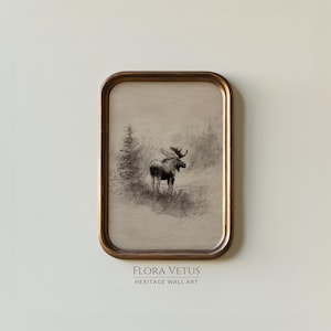 May include: A framed vintage print featuring a detailed pencil sketch of a moose in a natural landscape. The artwork is set within a rectangular, gold-toned frame. The text "FLORA VETUS HERITAGE WALL ART" is printed at the bottom.