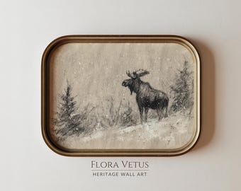 May include: A framed pencil sketch of a moose in a snowy landscape. The artwork features a detailed depiction of the moose with antlers, set against a backdrop of pine trees and falling snow. The frame is a gold colour, and the text "FLORA VETUS HERITAGE WALL ART" is at the bottom.