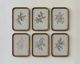 May include: A set of six rectangular wall art pieces in gold frames, each featuring a botanical illustration on a light grey background. The prints depict various plant sprigs including pine, holly, mistletoe, and other foliage.