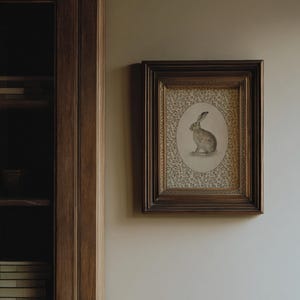 Hare wall art displayed on a narrow wall near a bookcase, evoking a quiet interior setting.