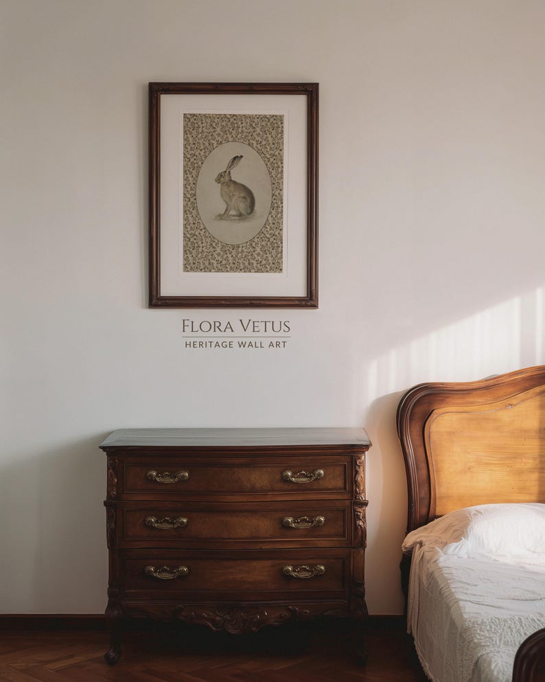 Framed hare artwork above a wooden dresser in a softly lit bedroom with a country house atmosphere.
