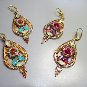 Può includere: Tre paia di orecchini a forma di lacrima con montature in metallo dorato. Ogni orecchino presenta una varietà di perline e cristalli colorati, tra cui turchese, rosa e arancio.