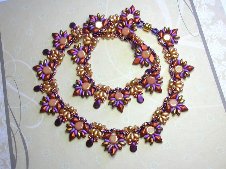 May include: A beaded necklace and matching choker set with a geometric starburst design. The beads are in shades of gold, purple, and orange.