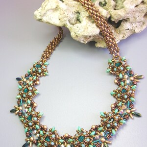 May include: A copper and green beaded necklace with a floral design. The necklace is made with small, round beads and features a repeating pattern of flowers.