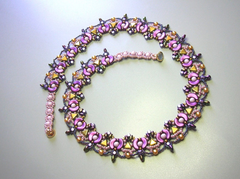 Op de afbeelding: Een paarse en gouden kralenketting met een bloemenmotief. De ketting is gemaakt van kleine, ronde kralen en heeft een delicate, vrouwelijke uitstraling.