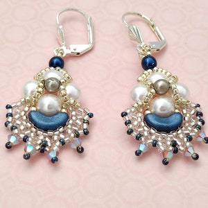 Peut inclure: Une paire de boucles d'oreilles pendantes avec une fermeture à crochet argentée. Les boucles d'oreilles présentent un motif de perles bleues, blanches et dorées avec une goutte de cristal.