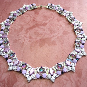 May include: A delicate necklace with a geometric design featuring white, purple, and iridescent beads. The necklace is made with a variety of beads, including faceted, round, and irregular shapes.