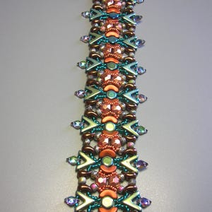 Könnte beinhalten: Ein Armband mit Perlen in einem geometrischen Muster in Braun-, Orange-, Türkis- und Grüntönen. Das Armband ist aus kleinen, facettierten Perlen gefertigt und hat einen Verschluss.
