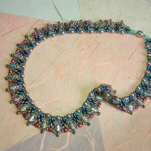 Puede incluir: Un collar de cuentas con un dise&ntilde;o graduado que presenta cuentas azules, marrones y rosas. El collar est&aacute; hecho con cuentas de diferentes tama&ntilde;os y tiene un aspecto delicado y femenino.