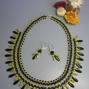 May include: A black and yellow beaded necklace with matching earrings. The necklace has a fringe of black and yellow beads.