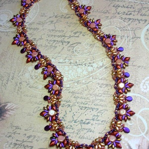 May include: A beaded necklace with a geometric design featuring purple, brown, and gold beads. The necklace is made with small, faceted beads and has a delicate, intricate design.