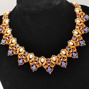 May include: A gold and white beaded necklace with blue accents. The necklace is made of small, round beads and has a delicate, feminine design.