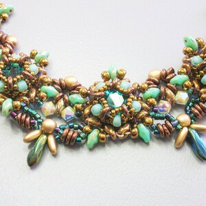 May include: A multi-strand necklace with a central cluster of green and gold beads. The necklace is made with a variety of beads, including round, teardrop, and faceted beads.