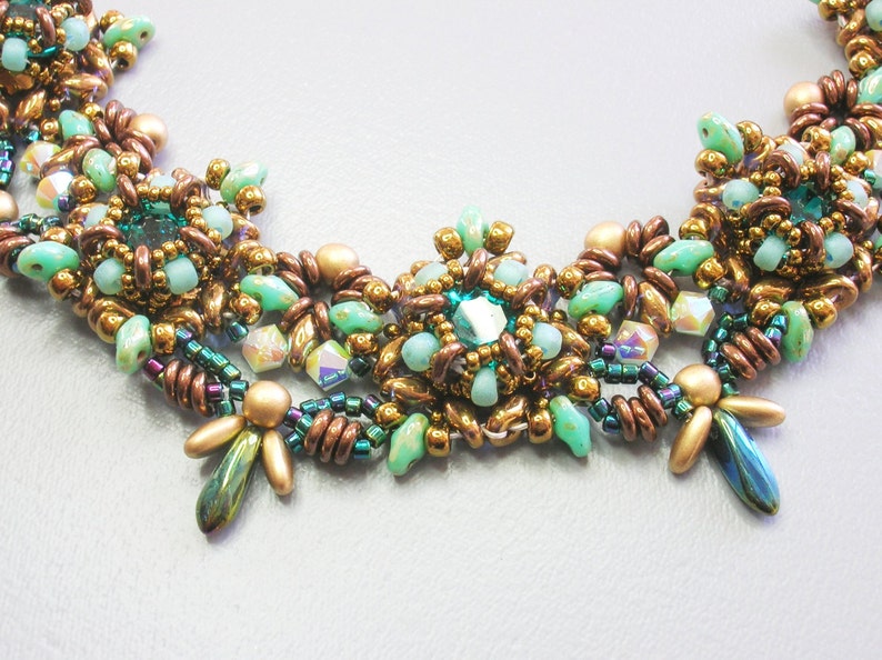 May include: A multi-strand necklace with a central cluster of green and gold beads. The necklace is made with a variety of beads, including round, teardrop, and faceted beads.