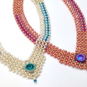 Op de afbeelding: Twee kralenkettingen met een traanvormige hanger. De ene ketting is gemaakt met witte en blauwe kralen, de andere met roze en gouden kralen.