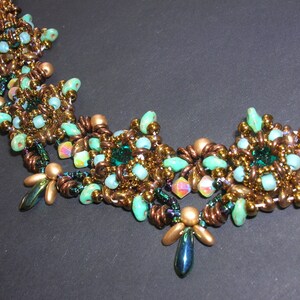 May include: A beaded necklace with a copper and green color scheme. The necklace features a repeating pattern of small, round beads and larger, faceted beads.