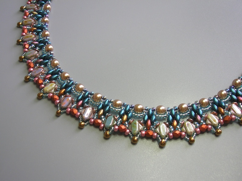 Puede incluir: Un collar de cuentas de m&uacute;ltiples hilos con un esquema de color turquesa, rosa y dorado. El collar presenta una variedad de cuentas, incluyendo formas redondas, ovaladas y de l&aacute;grima.