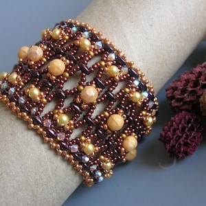 May include: A brown and gold beaded bracelet with a woven pattern. The bracelet is made with small, round beads and larger, round beads.