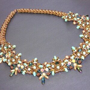 May include: A brown and green beaded necklace with a delicate, intricate design. The necklace features small, round beads in shades of brown, green, and turquoise, arranged in a pattern of swirling, floral motifs. The necklace is approximately 18 inches long and is perfect for adding a touch of elegance to any outfit.
