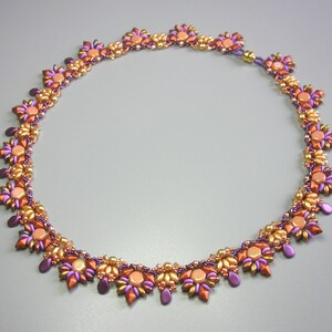 May include: A beaded necklace with a gold and purple color scheme. The necklace is made of small, round beads arranged in a floral pattern.