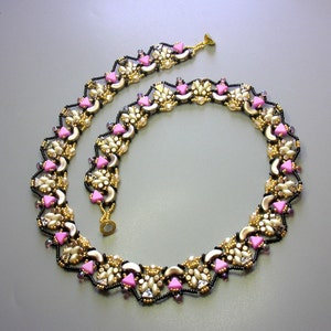 Könnte beinhalten: Eine zarte Halskette aus schwarzen, goldenen und rosafarbenen Perlen in einem geometrischen Muster.