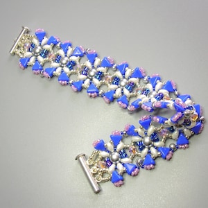 以下が含まれることがあります： ピンクのアクセントが付いた青と白のビーズブレスレット。ブレスレットは小さな丸いビーズで作られており、シルバーの留め具が付いています。