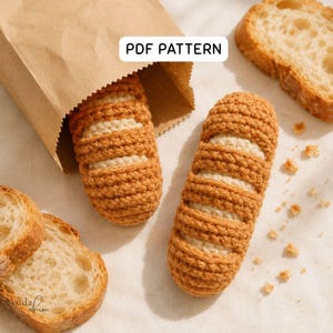Può includere: Due repliche di baguette all'uncinetto con crosta marrone dorato e interno color crema, una parzialmente all'interno di un sacchetto di carta marrone. Il testo PDF PATTERN è visibile. Fette di pane vero e briciole sono sparse intorno.