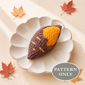 Pode incluir: Uma batata-doce de crochê com exterior castanho-escuro com detalhes amarelos e interior laranja brilhante, sobre um prato de cerâmica recortado. A imagem inclui o texto "PATTERN ONLY" numa sobreposição oval cinzenta.