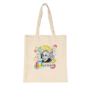 May include: A cream-colored tote bag featuring a colorful collage of images, including a portrait of Albert Einstein with diamond-shaped eyes and his tongue out. The design includes geometric shapes, a clock, and the word "Excellence".